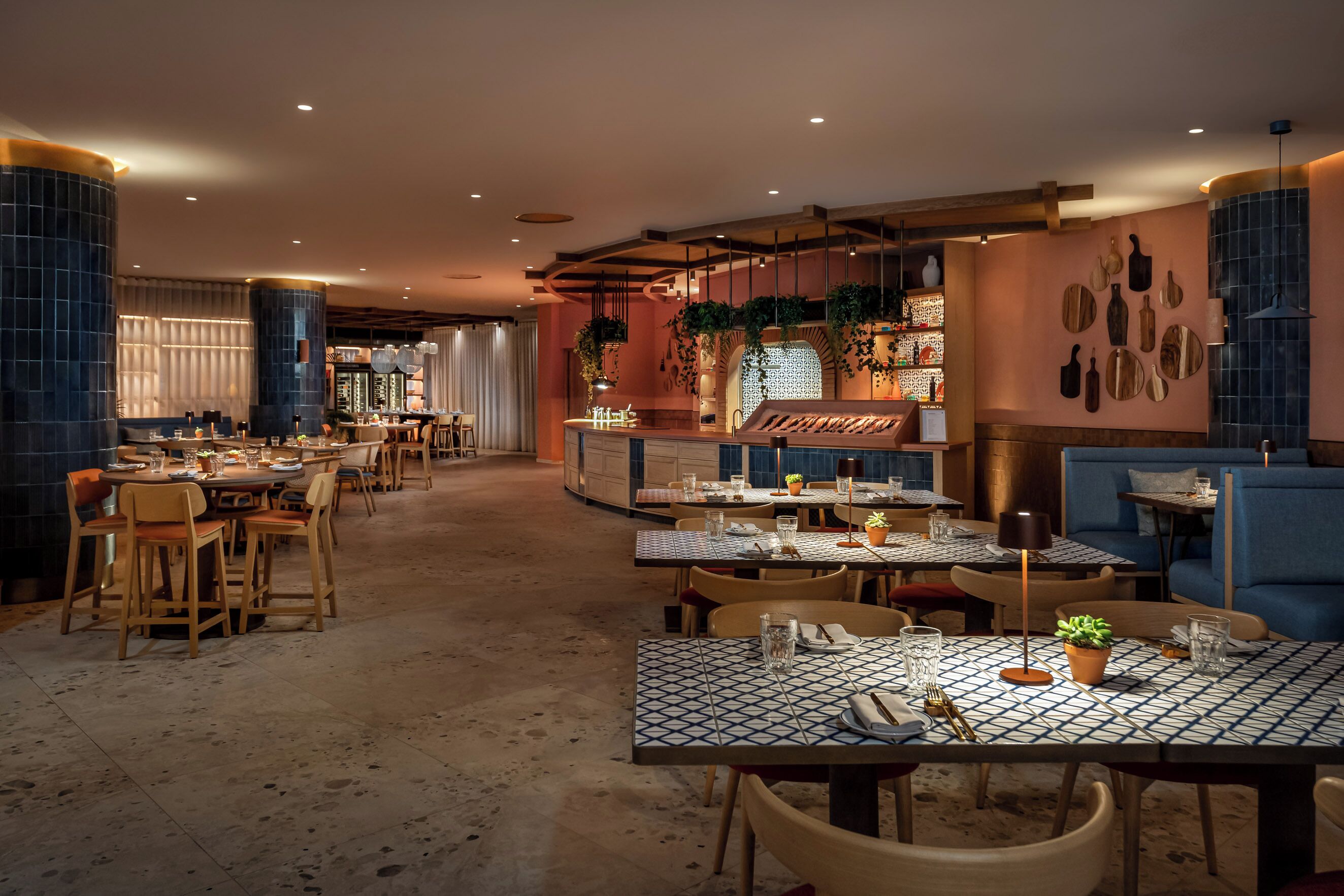 Un restaurant doté de nombreuses tables et chaises, d’un bar et d’un mur décoré d’ustensiles de cuisine.
