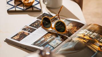 A table with a magazine, a cup of coffee, and a pair of sunglasses.