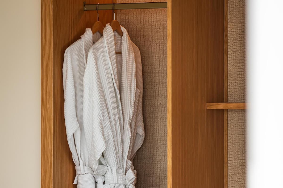 A wooden wardrobe with a hanging robe rack, a drawer, and a built-in appliance.
