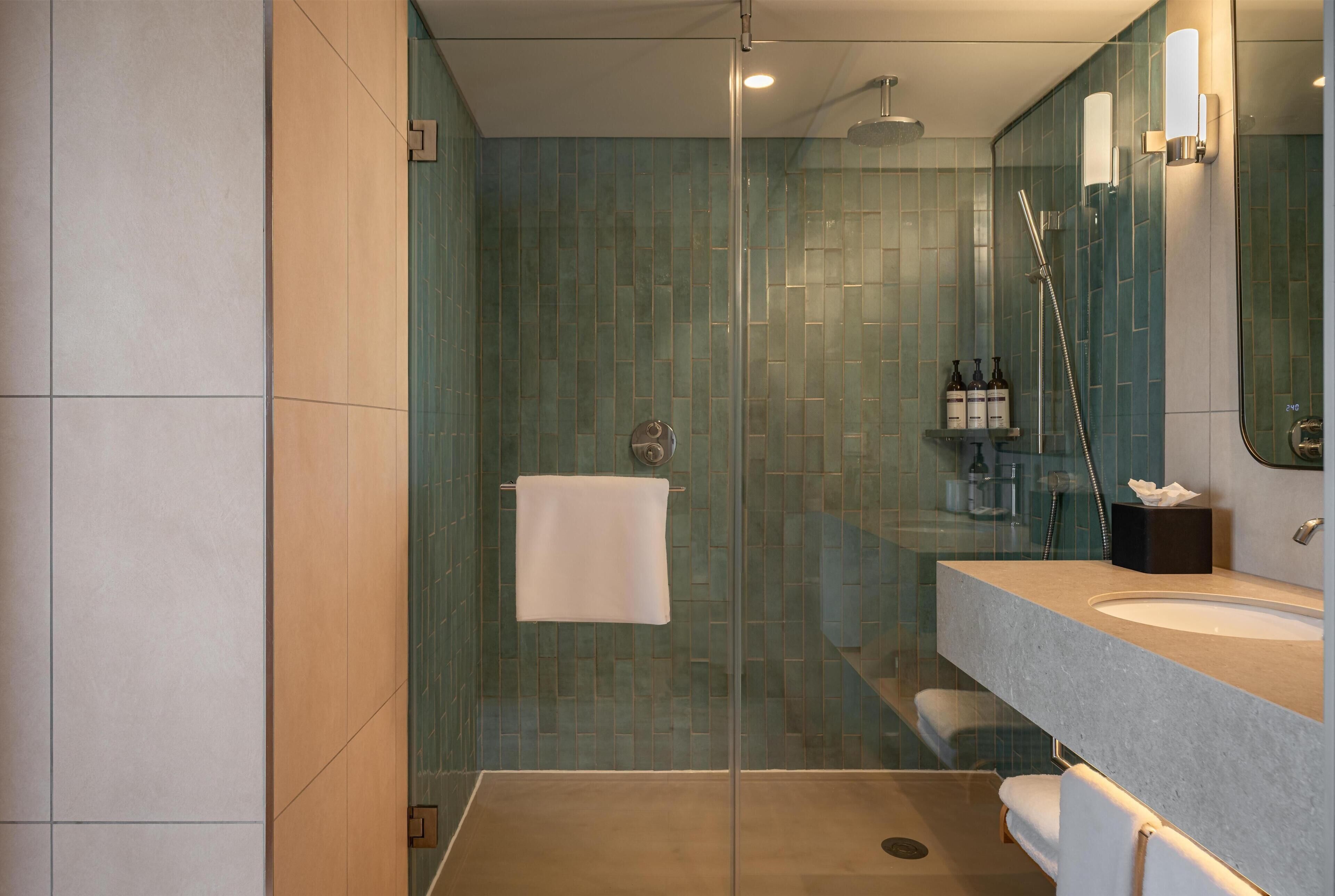 A modern bathroom with a glass shower enclosure, a sink, and a mirror.
