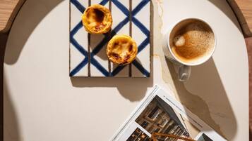 Una mesa con un plato de pasteles, una taza de café y una revista.