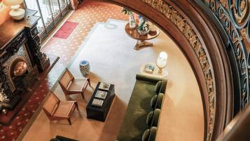 A grand lobby with a large, ornate mirror, a green sofa, and a wooden coffee table.