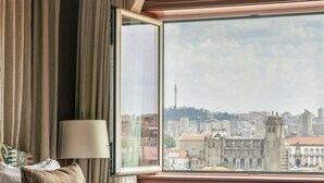Une chambre d’hôtel dotée d’une grande fenêtre donnant sur la ville, d’un lit recouvert d’une couverture verte et d’une lampe.