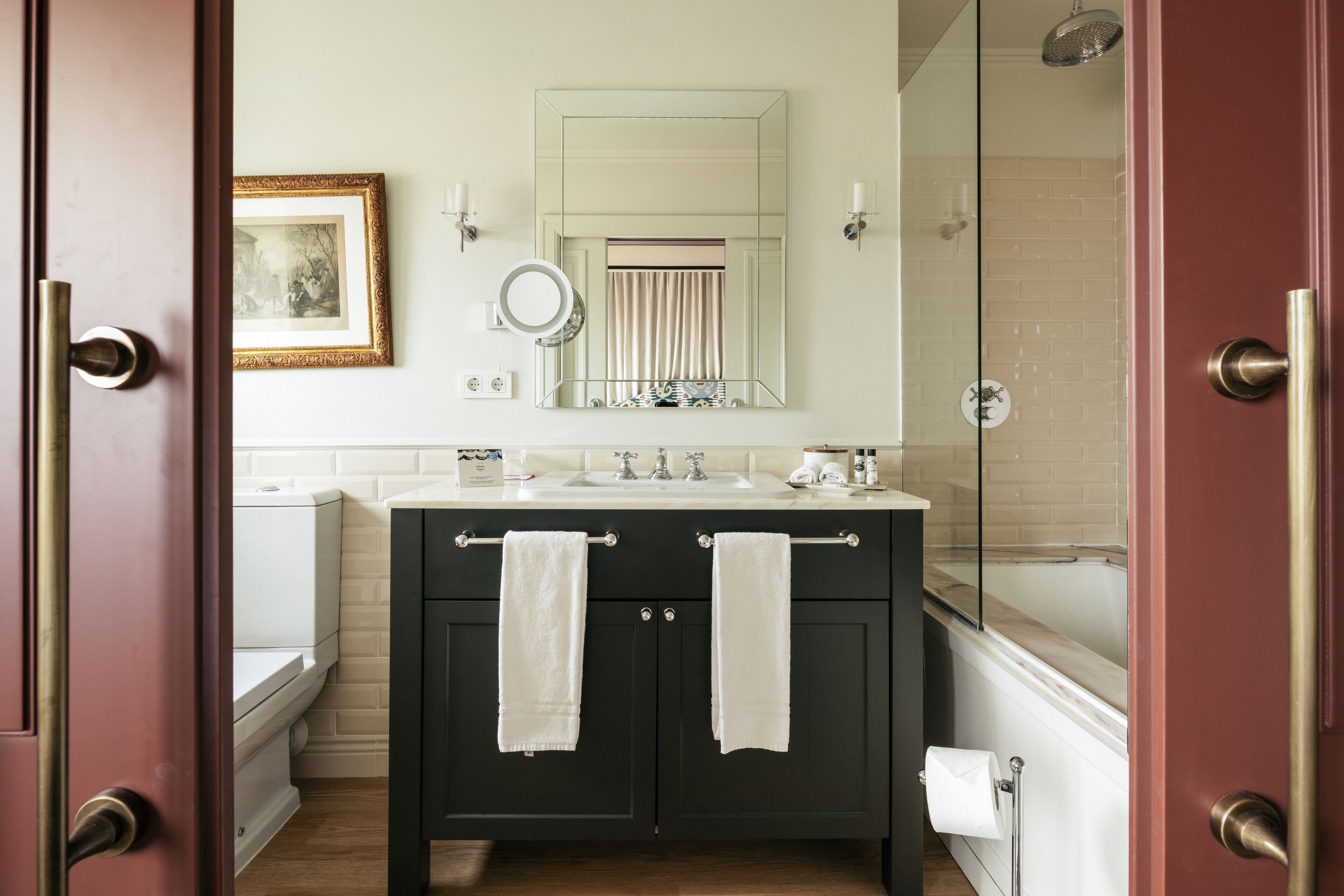 A bathroom with dark wooden cabinets, a white sink, a mirror, and a shower.