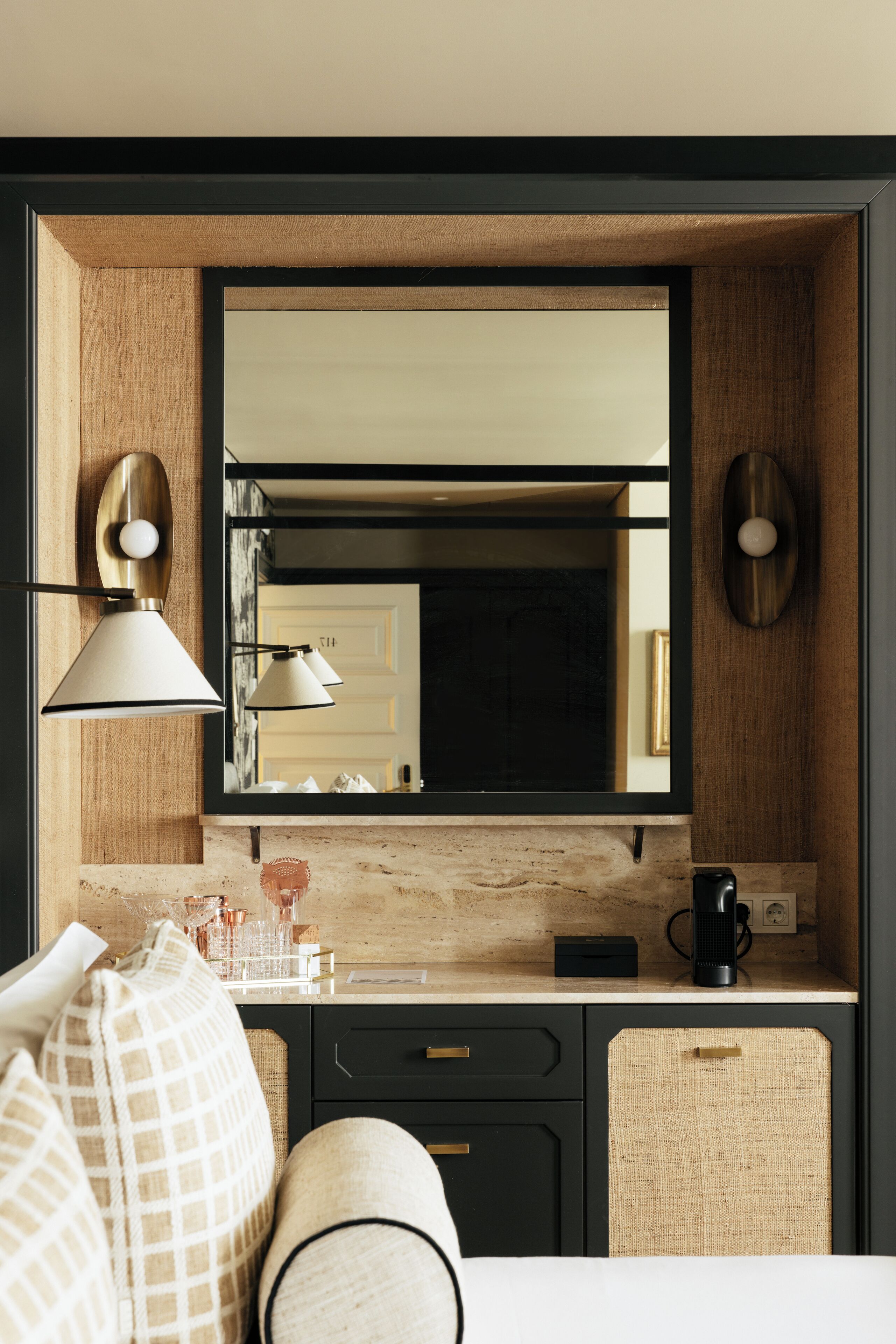 Una cocina moderna con un espejo grande, dos lámparas colgantes, una cafetera y un mueble pequeño.