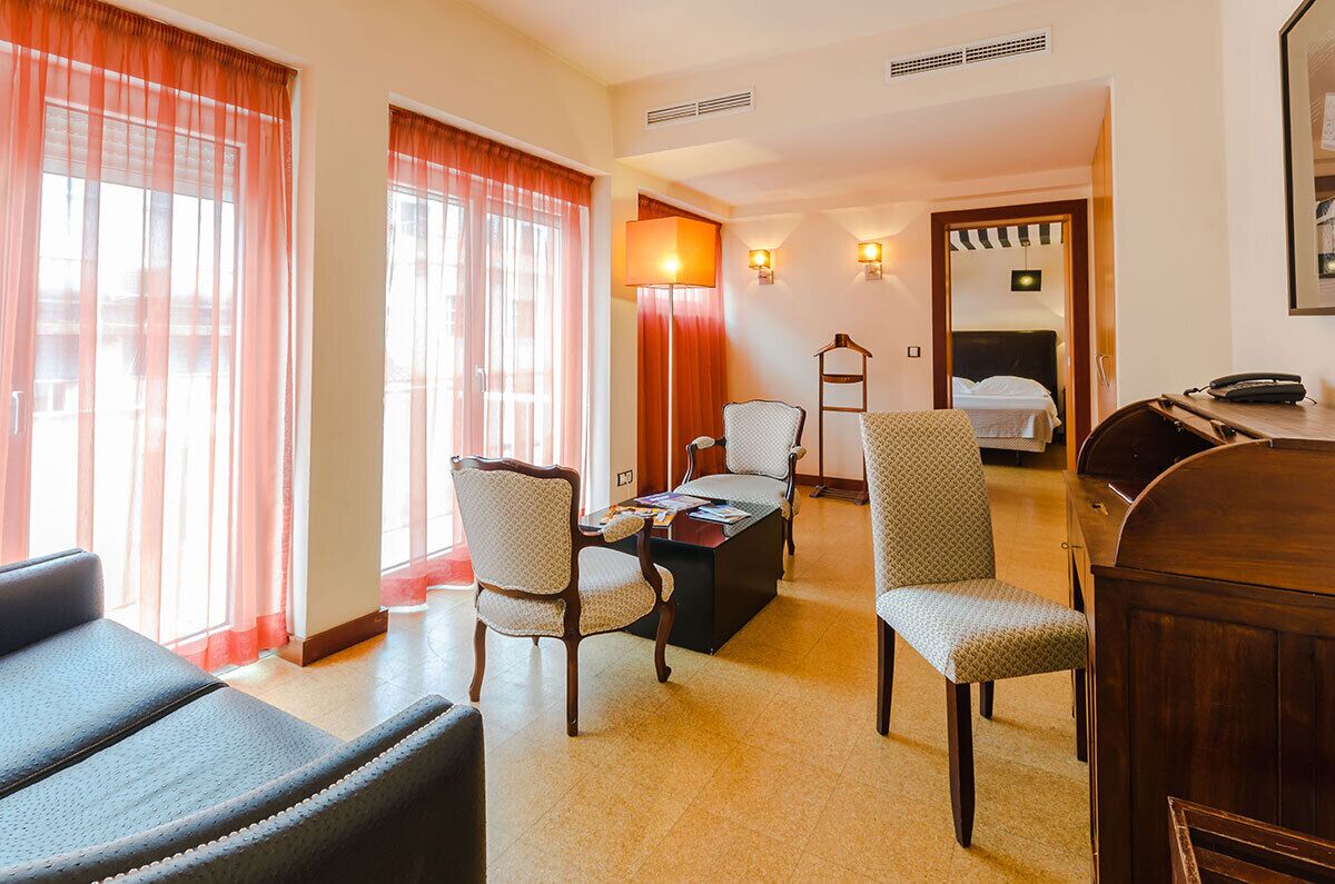 Quarto de hotel com área de jantar, cama, escrivaninha e telefone.