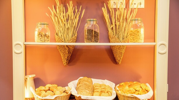 A bakery display with wheat stalks, jars of grains, and baskets of bread. - VIP Executive Saldanha Hotel (Lisbon)