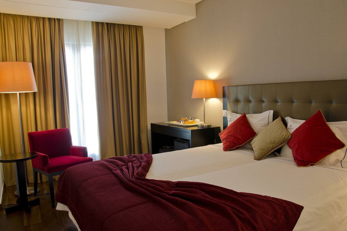 Una camera d'albergo con un letto, una scrivania, una sedia e due lampade.