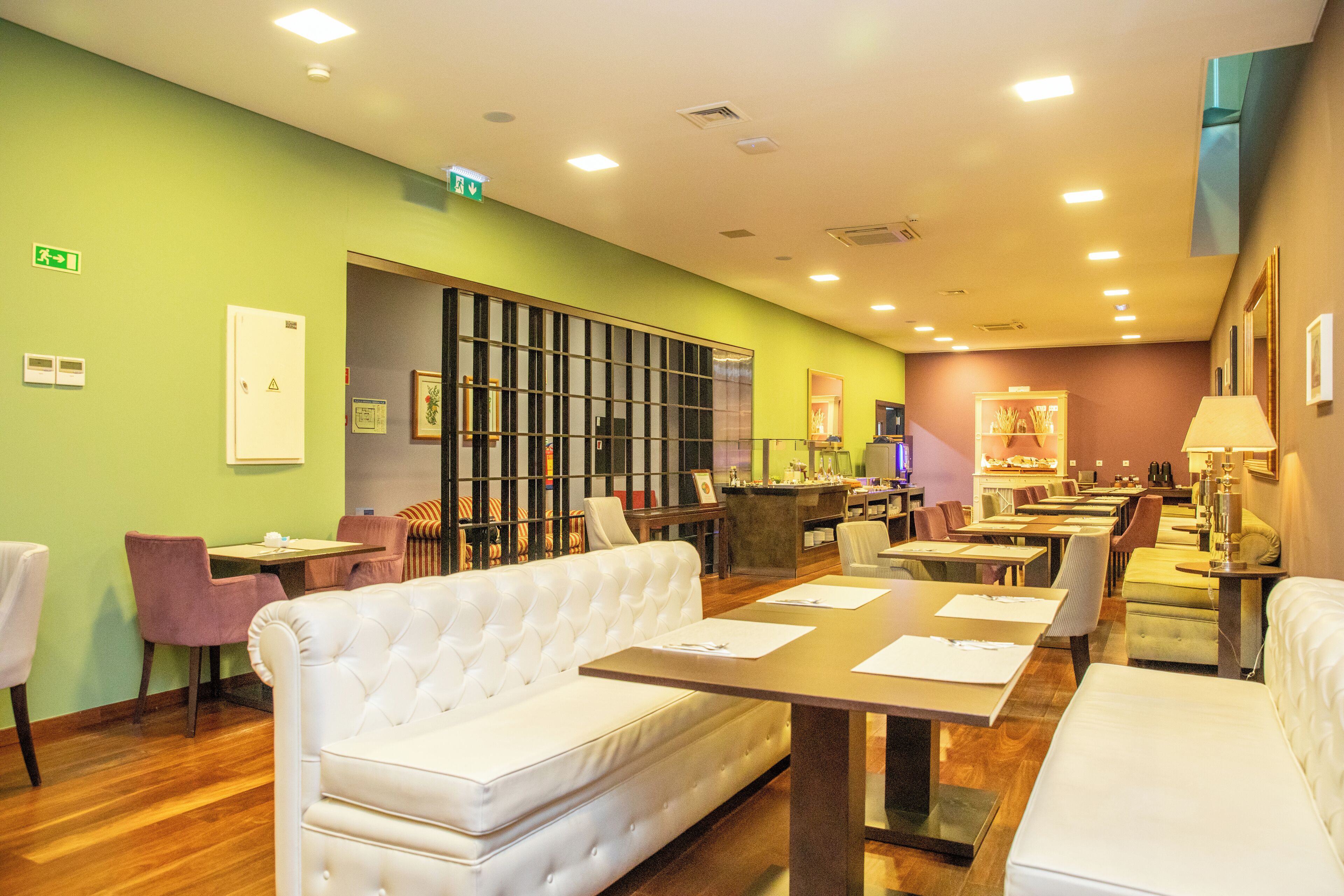 A hotel lobby with a green wall, a white sofa, and a reception desk.