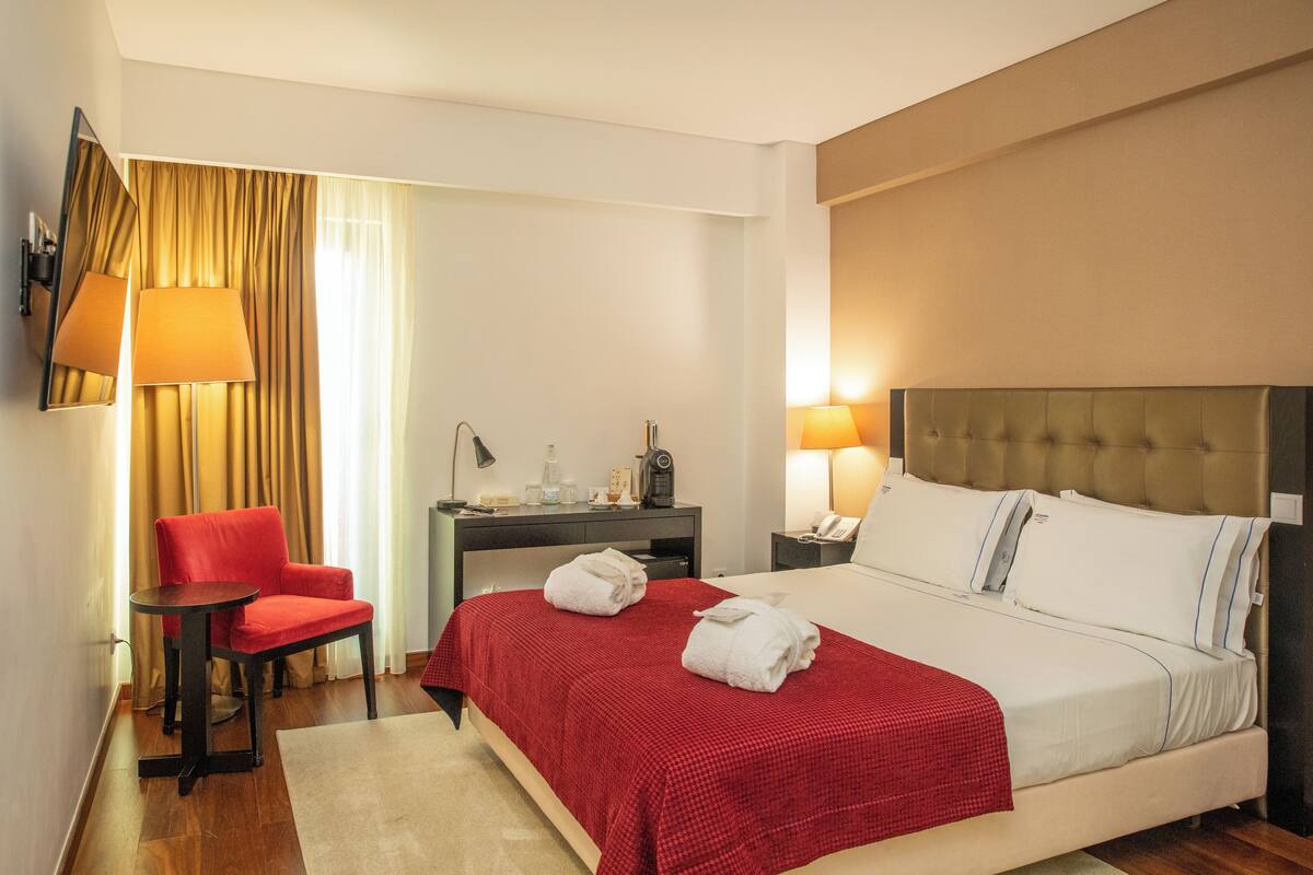 Una camera d'albergo con un letto, una scrivania, una sedia e uno specchio.