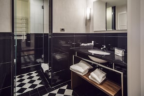 A modern bathroom with a black and white checkered floor, a glass shower enclosure, a black vanity with a sink, and a mirror above the sink.