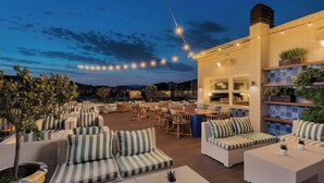 Une terrasse extérieure dotée d’espaces pour s’asseoir, d’un bar et offrant une vue sur le panorama urbain.