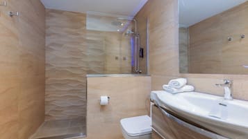 Un baño moderno con ducha envuelta en vidrio, un lavabo blanco y un inodoro.