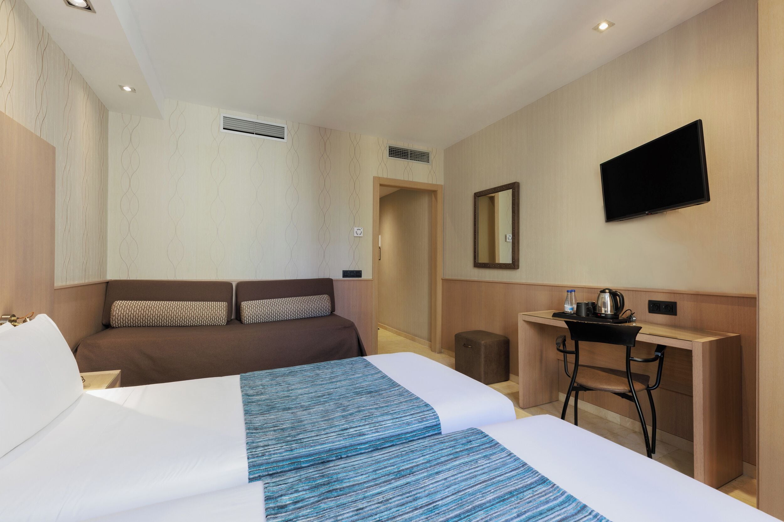 Een hotelkamer met twee bedden, een bureau, een stoel, een televisie en een spiegel.