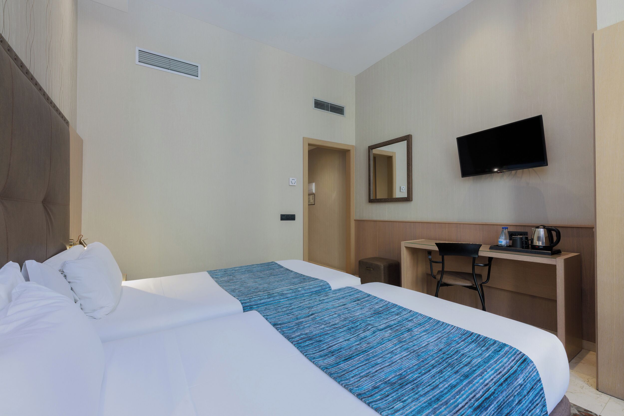Une chambre d’hôtel avec un grand lit, un bureau avec une chaise, une télévision et une machine à café.