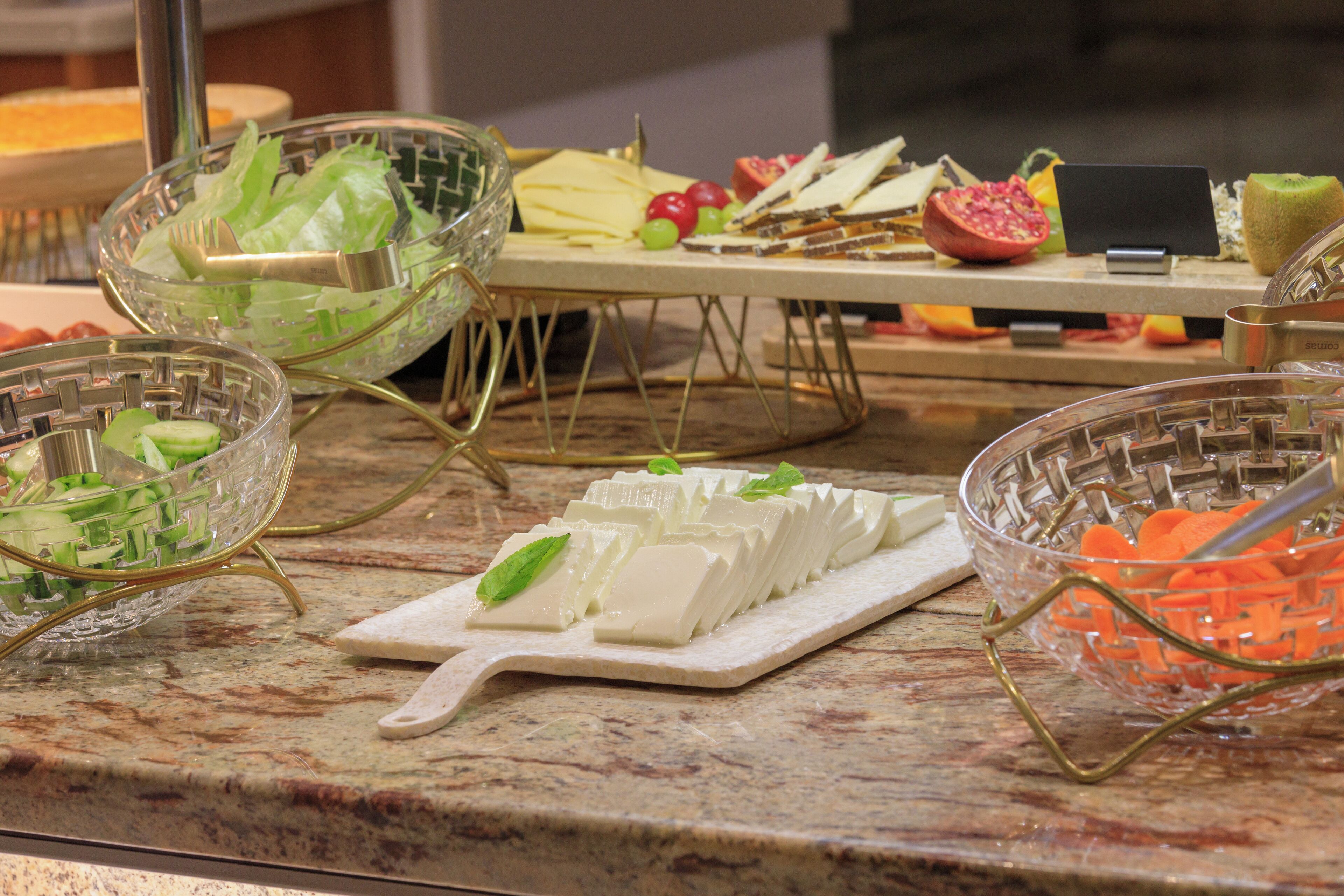 Un bufé con diversos alimentos, incluyendo queso, frutas y verduras.