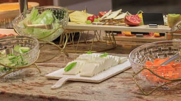 Un bufé con diversos alimentos, incluyendo queso, frutas y verduras.