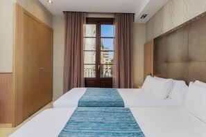 A hotel room with a large bed, a wardrobe, a view of the city through a window, and a headboard. - Hotel Gotico (Barcelona)