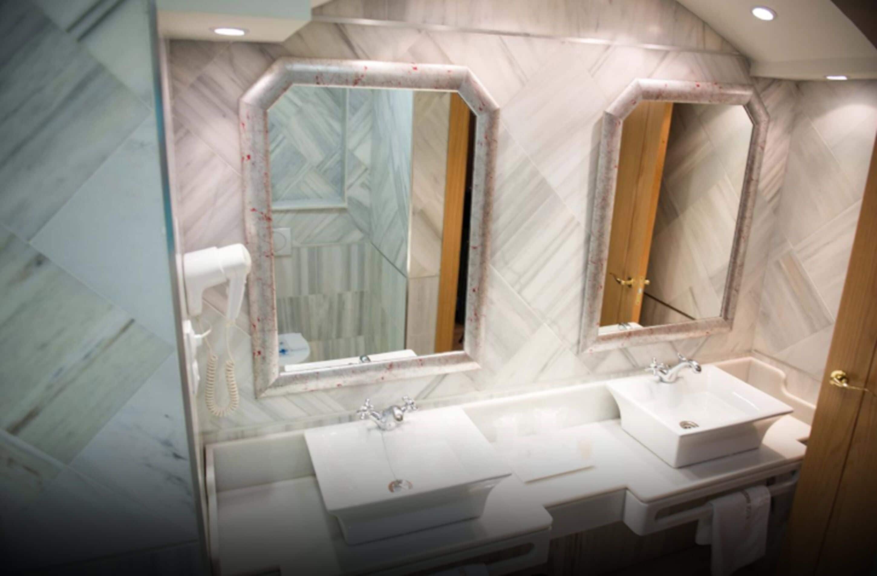Un baño con dos lavamanos, un espejo y un perchero para toallas.