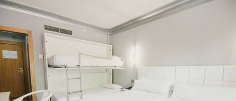 Habitación de hotel con literas, una cama individual, una silla y un escritorio.