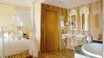 Un dormitorio con cama con dosel, una puerta de madera y un baño con lavabo y espejo.
