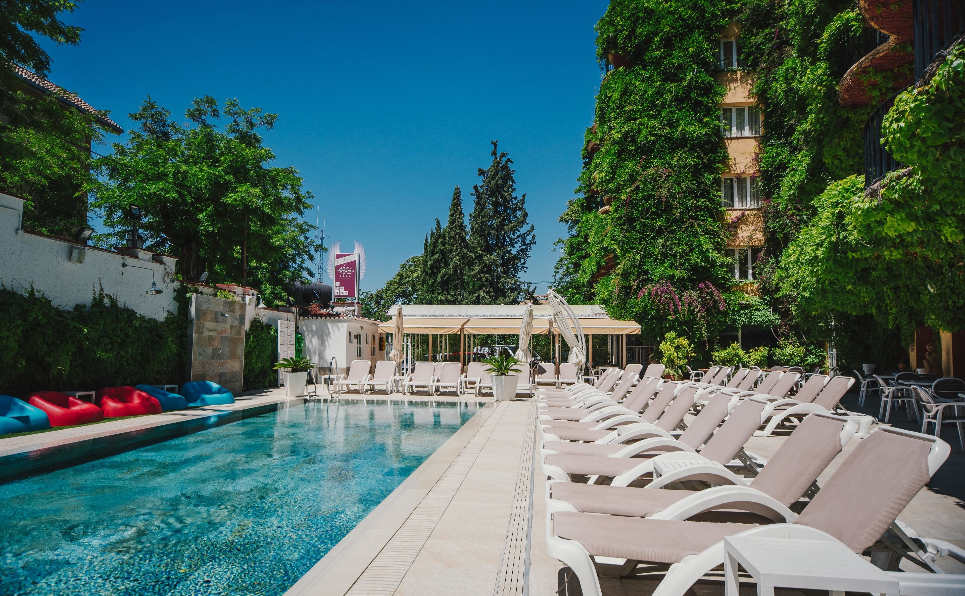 Un área de piscina con sillas de descanso y una zona de estar cubierta.