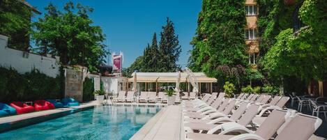 A pool area with lounge chairs and a covered seating area.