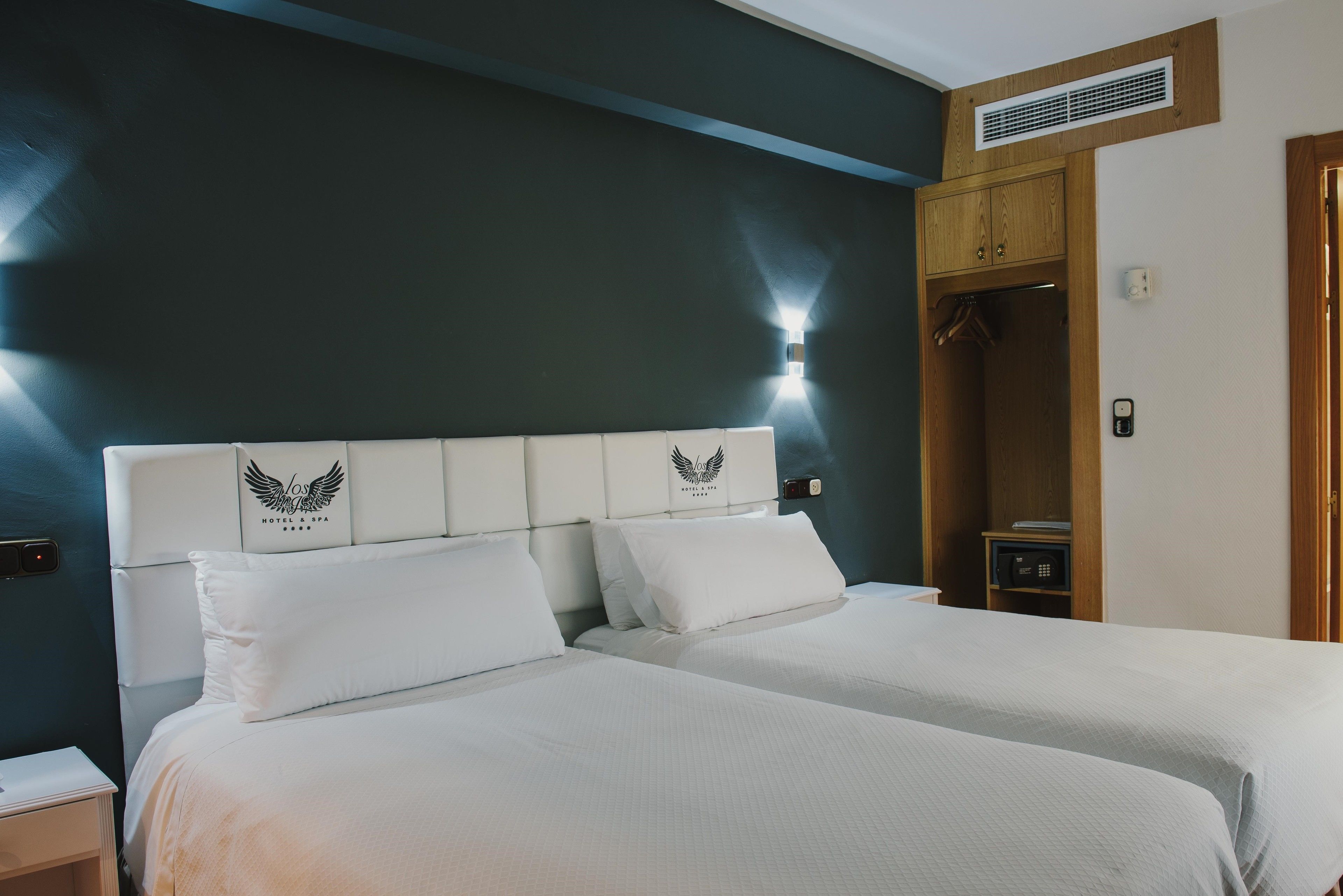 A hotel room with a large bed, a wardrobe, and a nightstand.