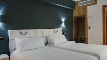 A hotel room with a large bed, a wardrobe, and a nightstand.