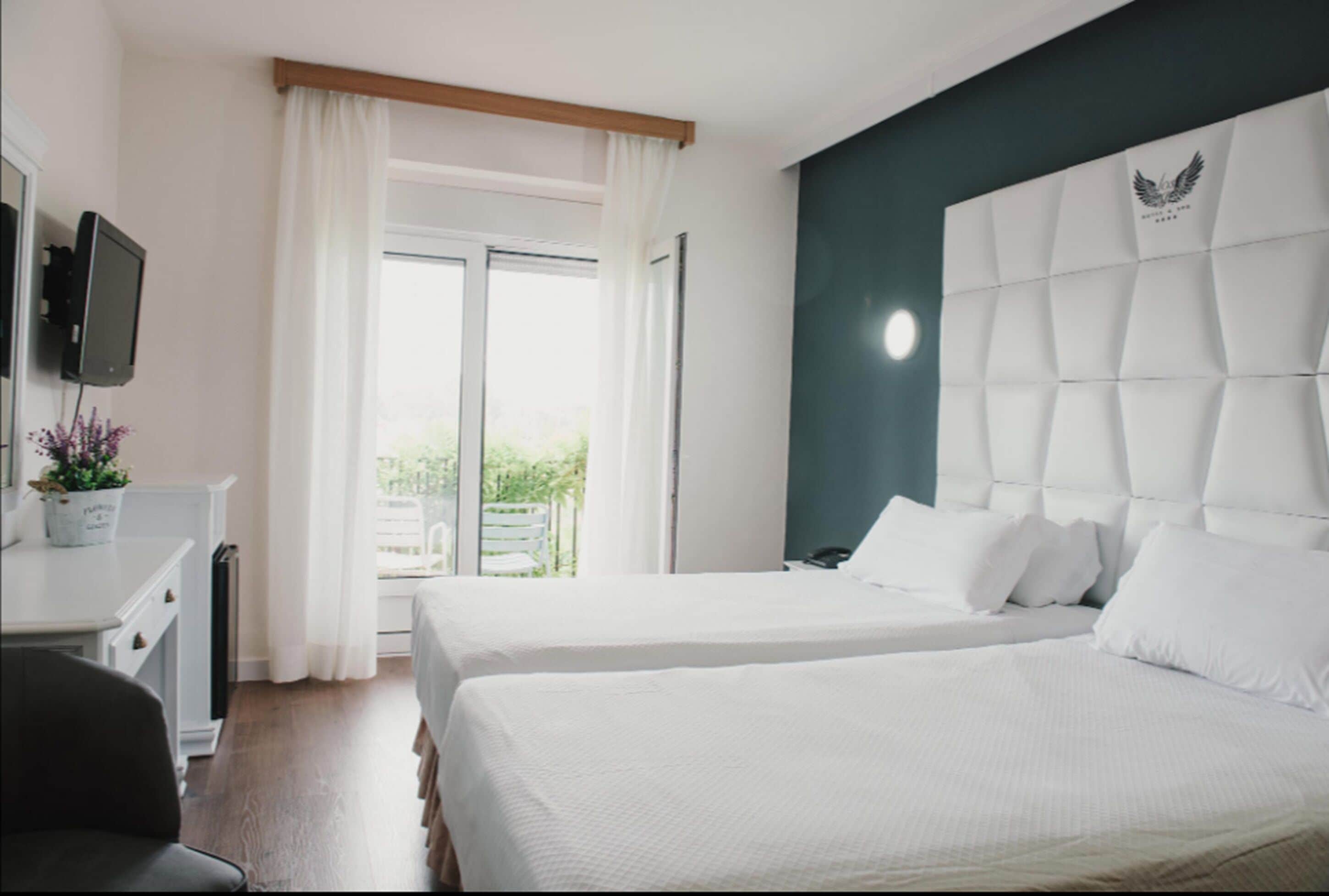 Habitación de hotel con dos camas, un escritorio, una silla, un televisor y vista a zonas verdes.