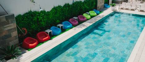 Una piscina con asientos flotantes de colores y una superficie de agua azul transparente.