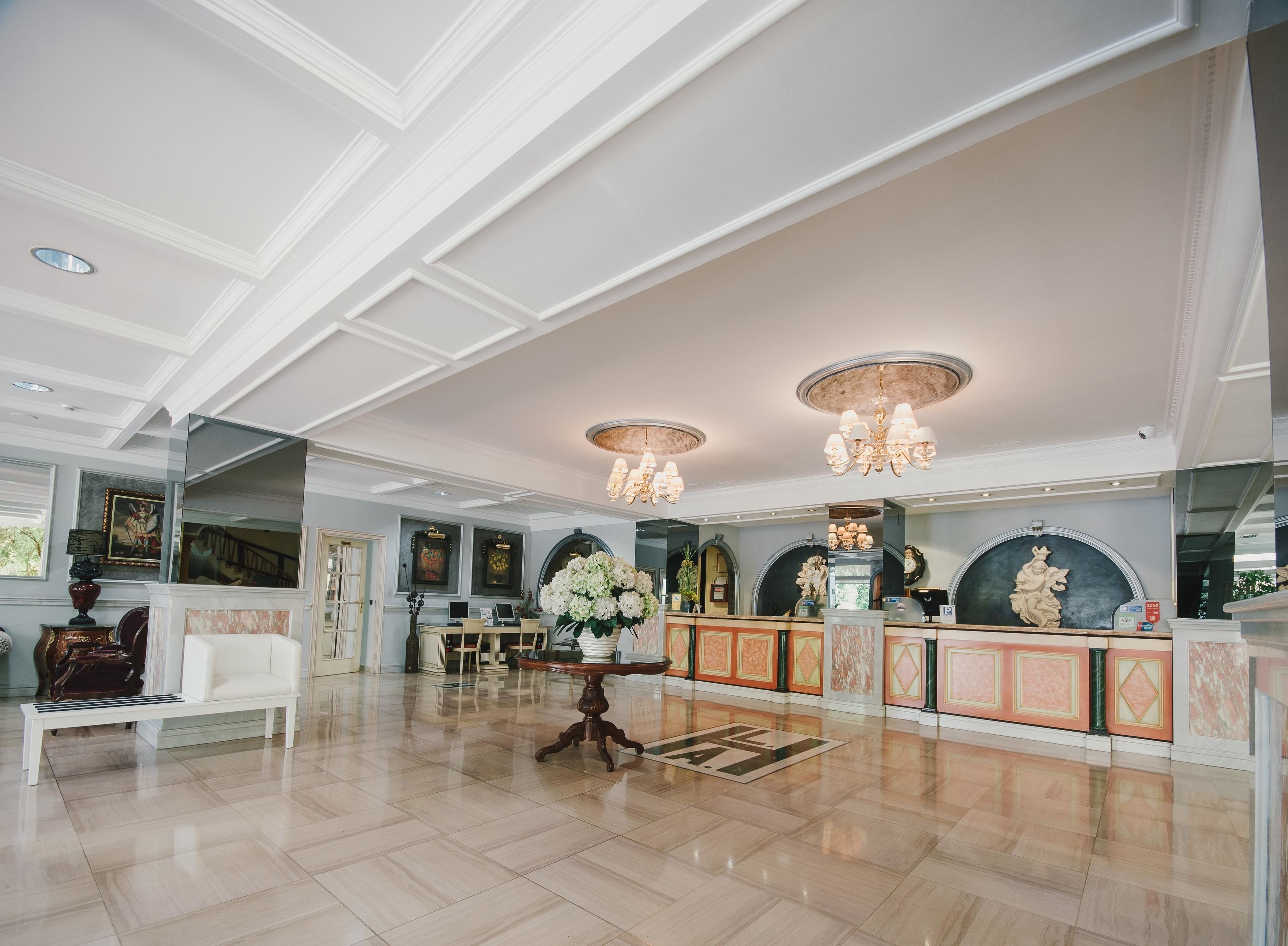 Een ruime lobby met een hoge plafond, kroonluchters, een receptiebalie en een zithoek.