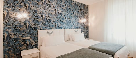 A hotel room with two beds, a nightstand, and a floral wallpaper.
