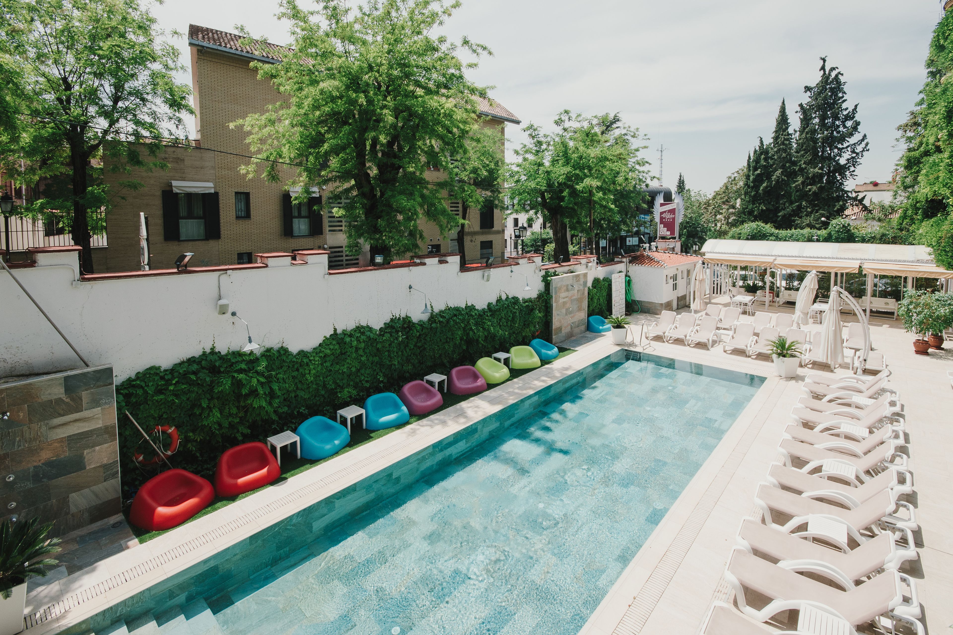 Una piscina con sillas de descanso coloridas y una zona de estar cubierta.