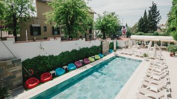 Una piscina con sillas de descanso coloridas y una zona de estar cubierta.