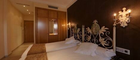 Habitación de hotel con dos camas, un armario de madera, un espejo y apliques de pared.