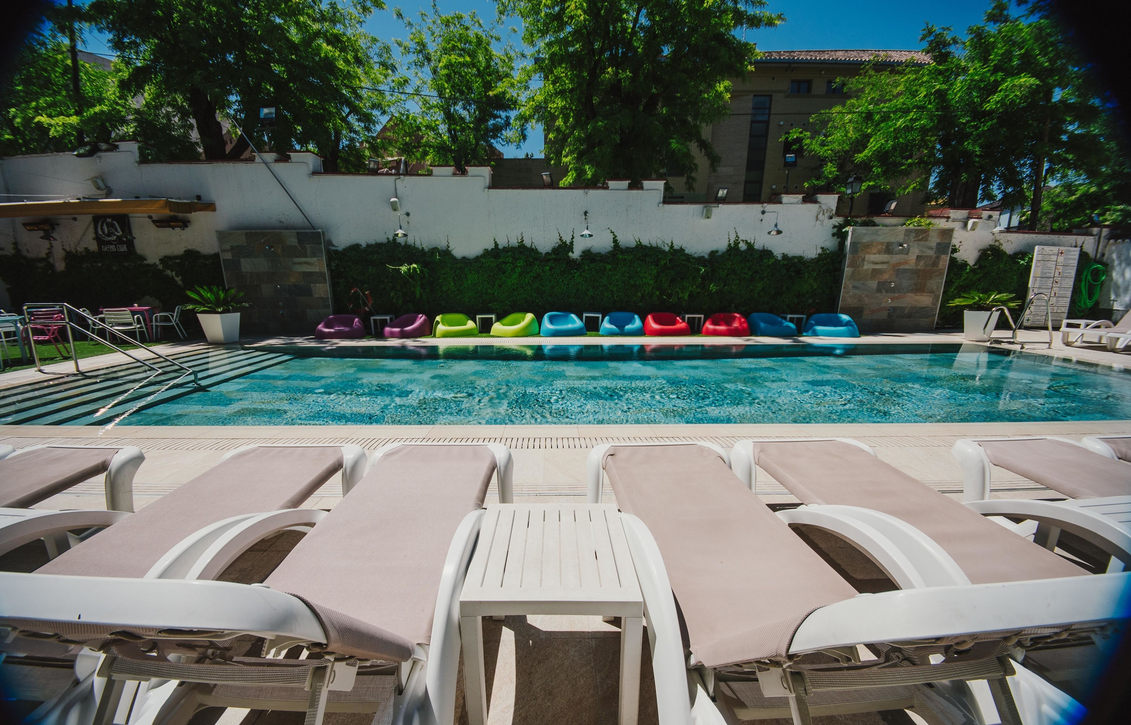 A swimming pool with lounge chairs and colorful inflatable rings.