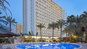 A hotel with a large pool area, palm trees, and lounge chairs. - Sol Pelícanos Ocas (Benidorm)