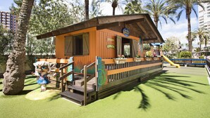 A wooden cabin with a deck, surrounded by palm trees and greenery. - Sol Pelícanos Ocas (Benidorm)