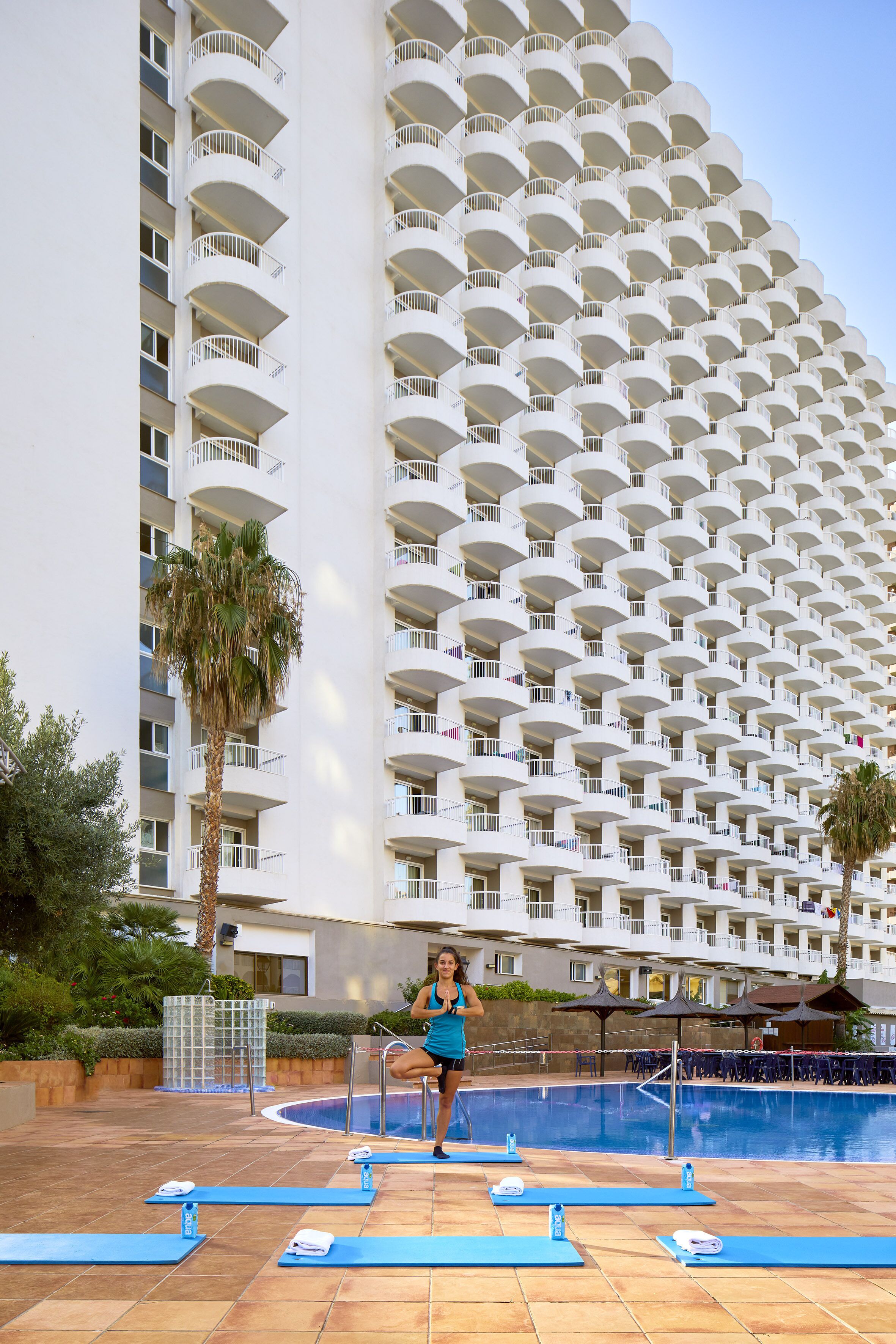 Un hotel con un amplio espacio de piscina, varios balcones y colchonetas de ejercicio.