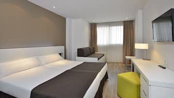 A hotel room with a bed, a sofa, a desk, and a TV.