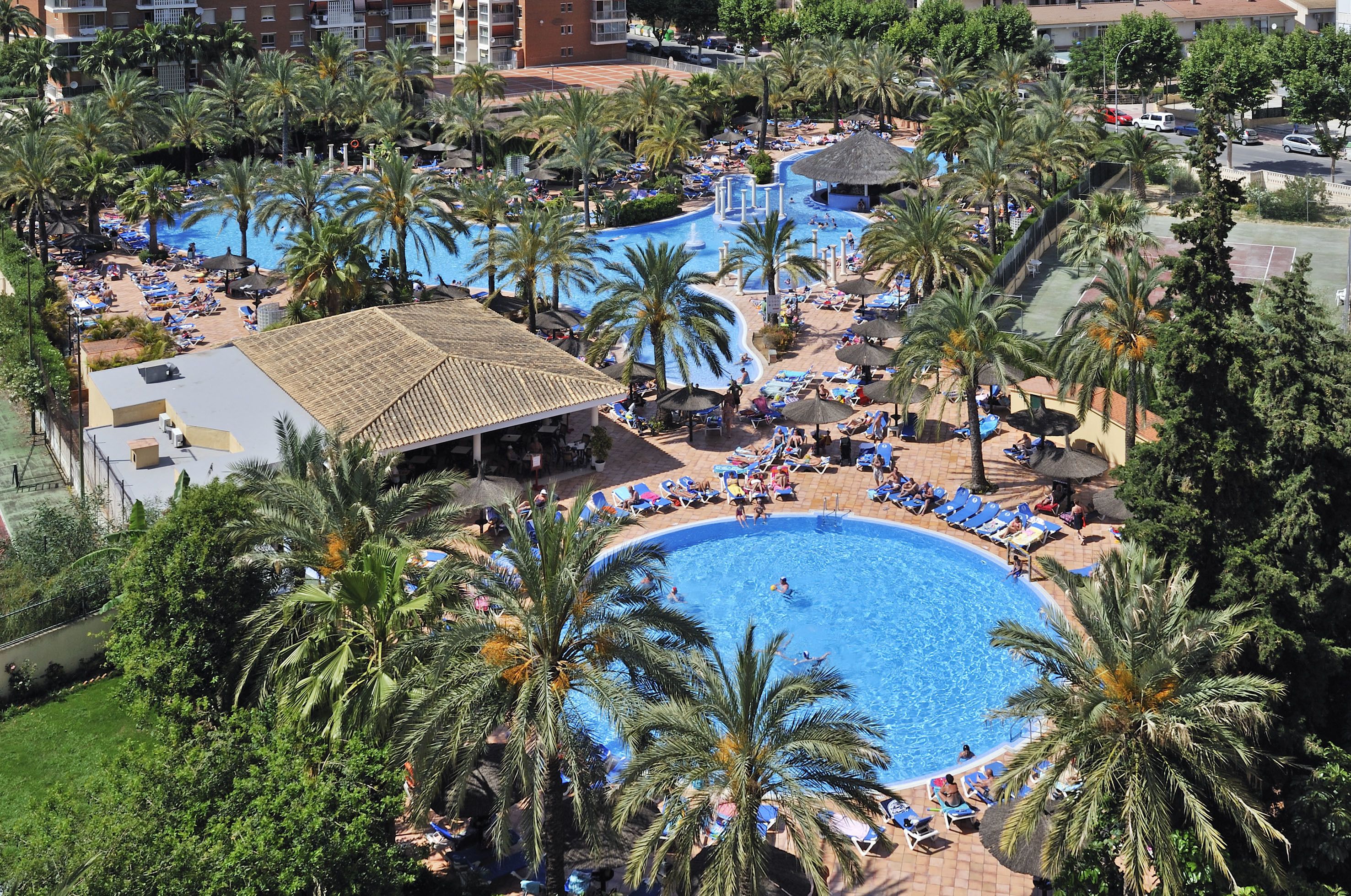 A resort with multiple swimming pools, palm trees, and sun loungers.