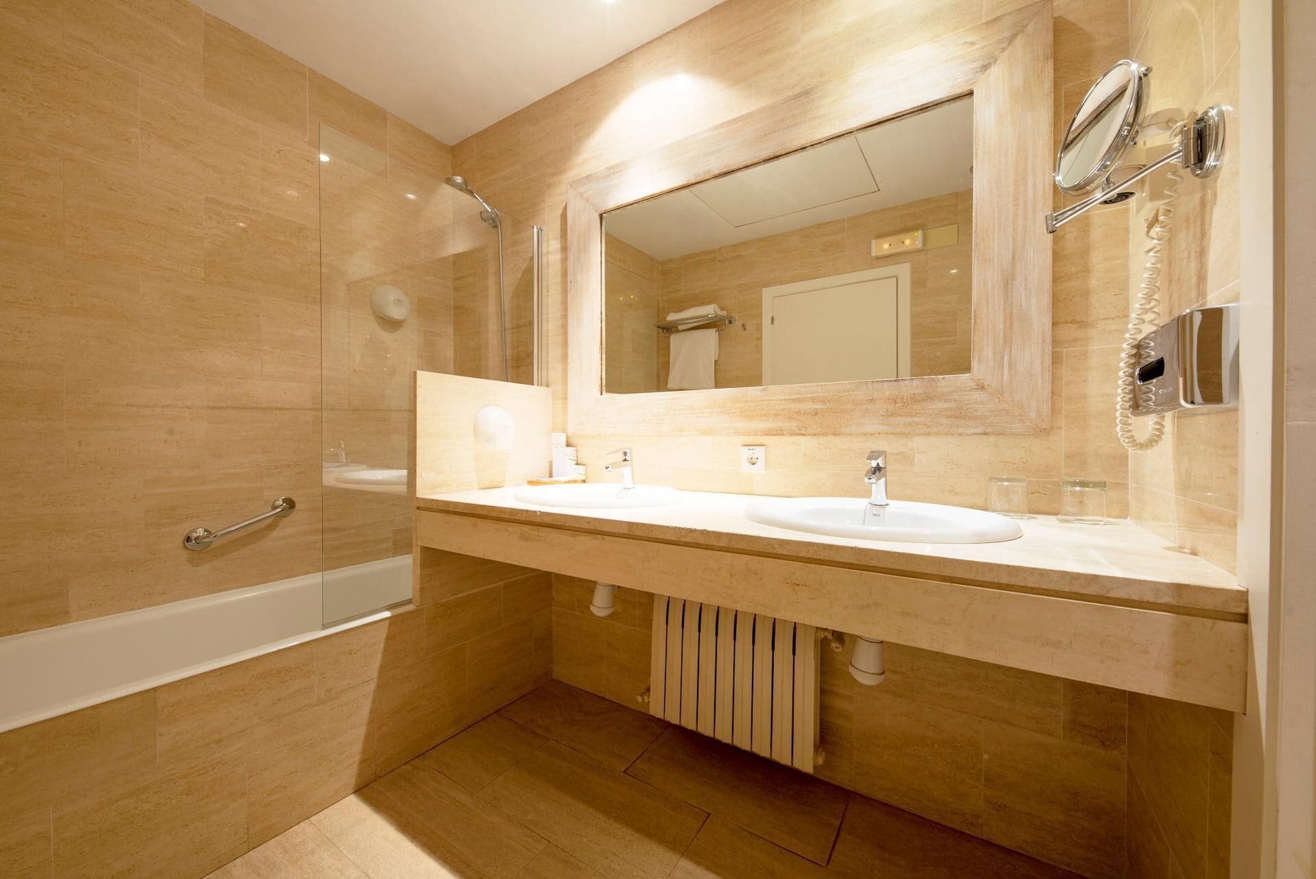 Une salle de bain moderne avec deux lavabos, un grand miroir et une douche.