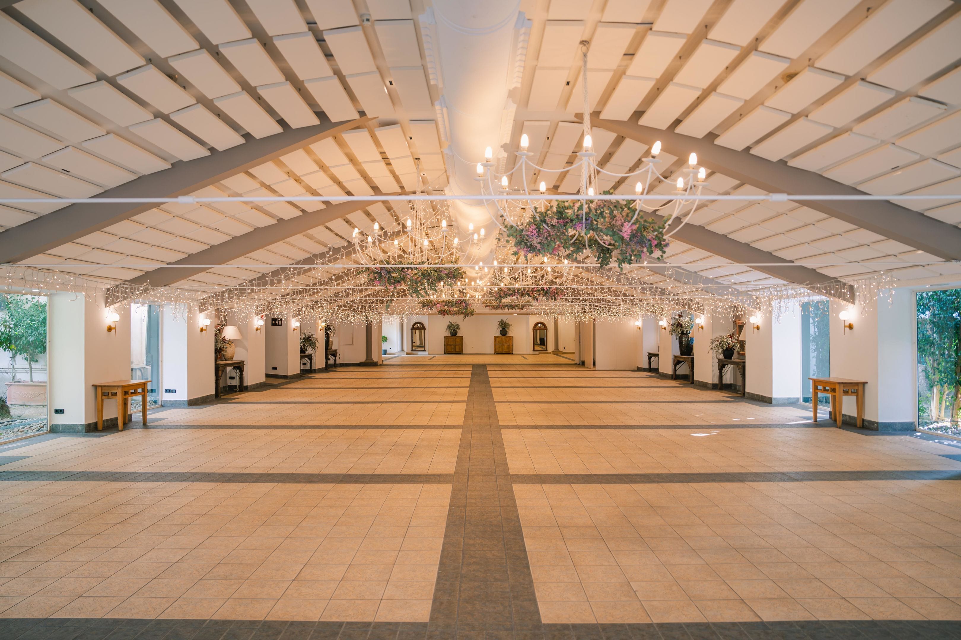 Un salón amplio con techo alto, candelabros y decoración floral.