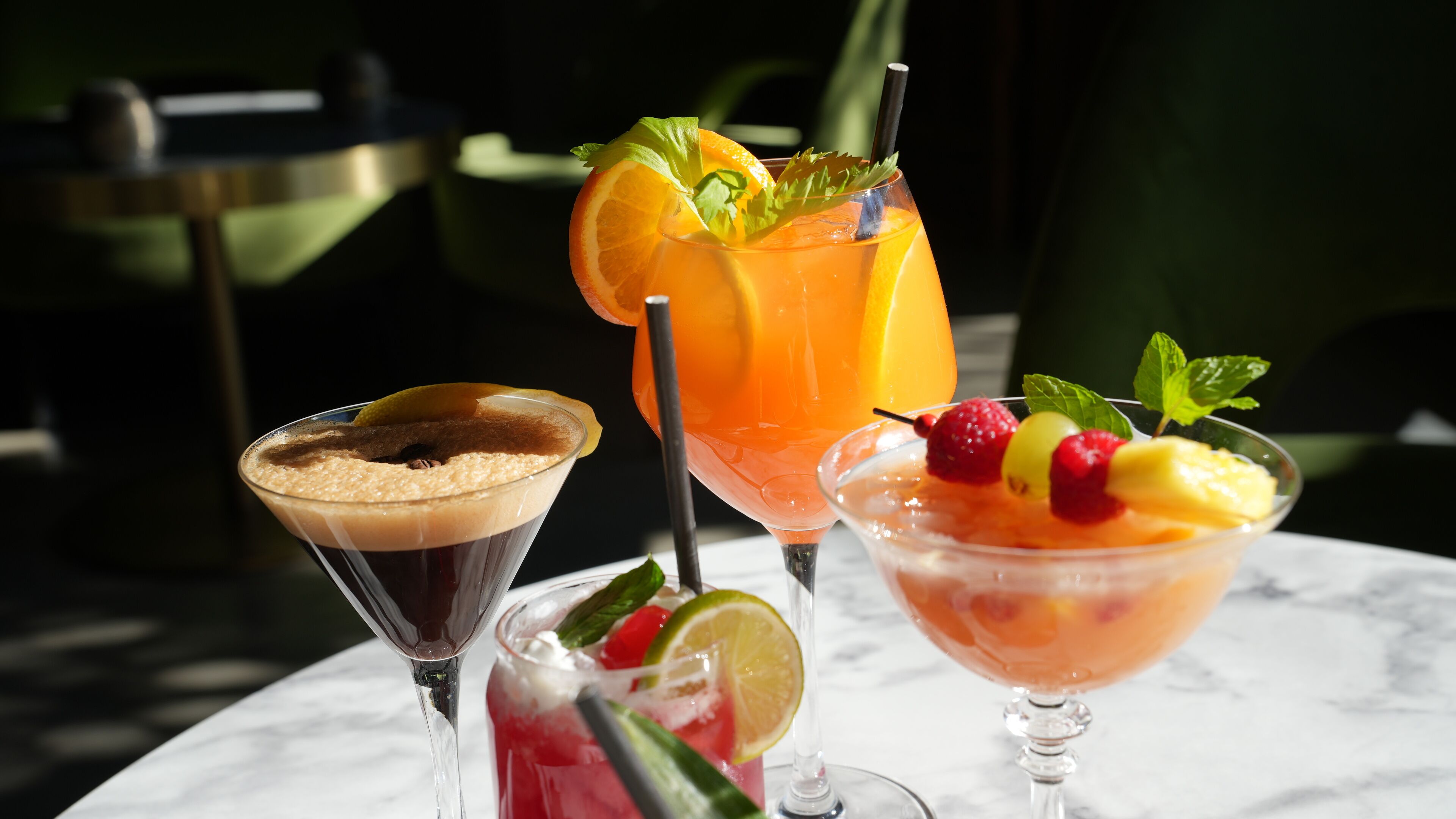 Three cocktails on a marble table.