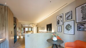 Un vestíbulo de hotel moderno con un mostrador de recepción de madera, una mesa redonda con un jarrón de flores e impresiones botánicas enmarcadas en la pared.
