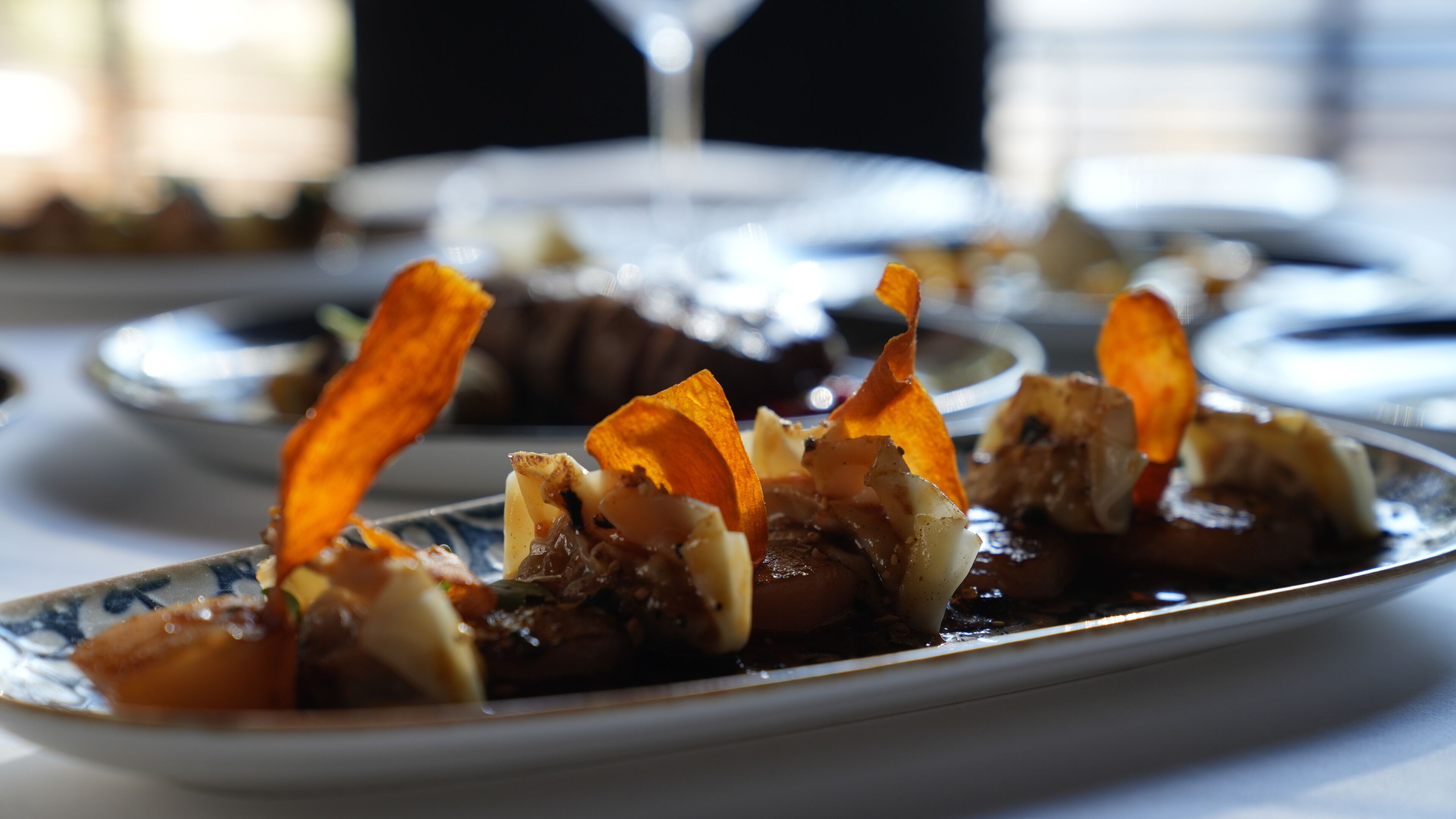 Una mesa de comedor con platos de comida, incluyendo un plato con cebollas y champiñones caramelizados.