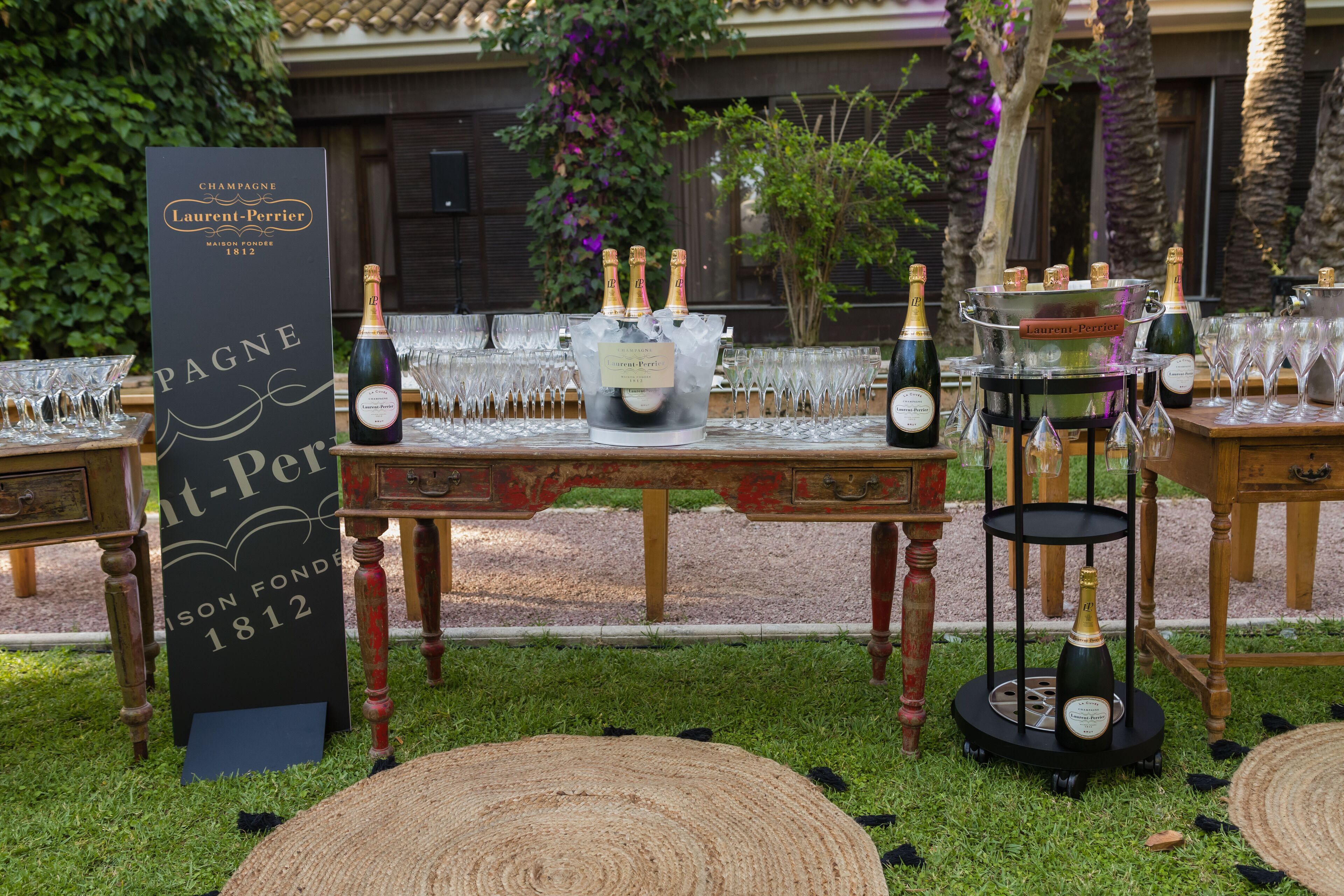 A table set with champagne bottles, glasses, and a sign for Laurent-Perrier 1812.