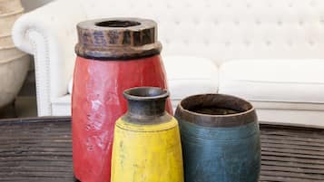 Tres macetas grandes de cerámica sobre una mesa, con un sofá blanco al fondo.