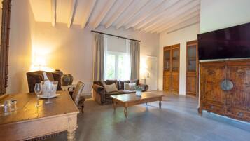 Een ruime woonkamer met een houten salontafel, banken en een televisie.